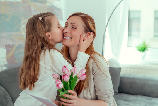 kind gratuliert mama zum muttertag mit blumen