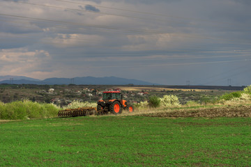 Farmer with tractor seeding crops at field