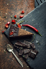 Fototapeta na wymiar Piece of dark chocolate cake with red hot pepper. The restaurant or cafe atmosphere. Retro. Vintage