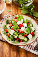 Fresh spinach salad with feta, cucumber and red paprika on a pla