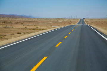 Fototapeta na wymiar Long empty asphalt road in desert with clear blue sky .