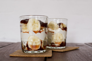 Two glass of cocktail, smoothies, with yogurt, and dessert are on the table in front of a white wall bar