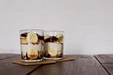 Two glass of cocktail, smoothies, with yogurt, and dessert are on the table in front of a white wall bar