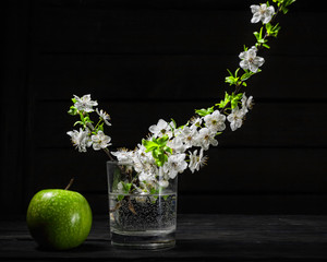 Green apples with blossoms on wooden table