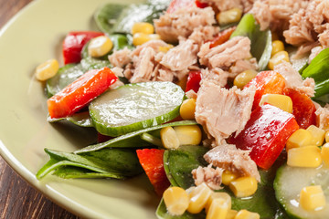 Fresh spinach salad with tuna, cucumber, corn, and red paprika on a plate