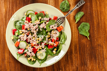 Fresh spinach salad with tuna, cucumber, corn, and red paprika o