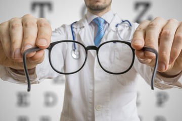 Oculist doctor is giving glasses to a patient. Eye sight testing concept.