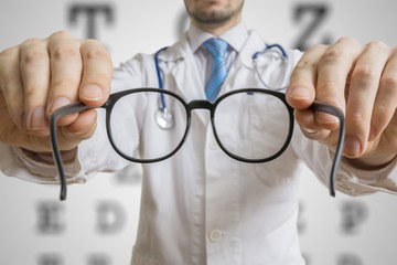 Oculist doctor is giving glasses to a patient. Eye sight testing concept.