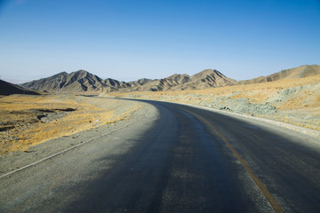 Obraz na płótnie Canvas Long empty curve asphalt road in desert with clear blue sky .