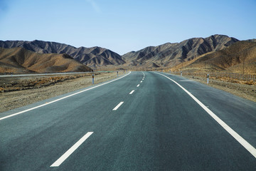 Long empty asphalt road in desert with  clear blue sky .