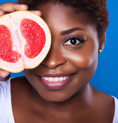 African-American woman with grapefruit on blue background, close