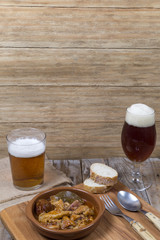 Wooden table with clay bowl with meat and beer glasses on an old wooden table
