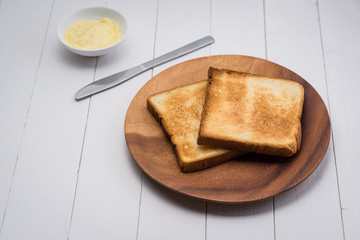 Close-up of slice of toast bread with butter on wood table