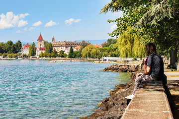 People sitting on Lake Geneva embankment at Chateau Ouchy Lausanne