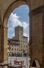 Fototapeta na wymiar Beautiful vertical view of Piazza Grande and Torre Lappoli tower, Arezzo, Tuscany, Italy, framed by an arch of Vasari's Palazzo delle Logge
