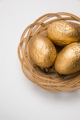 Golden Easter Eggs on whtite in wicker nest style bowl