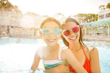 Happy mother and daughter playing in swimming pool.