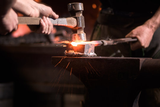 Farriers forging horseshoe on anvil