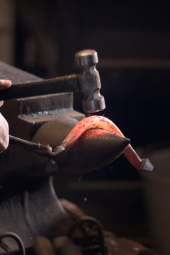 Farrier forging horseshoe on anvil