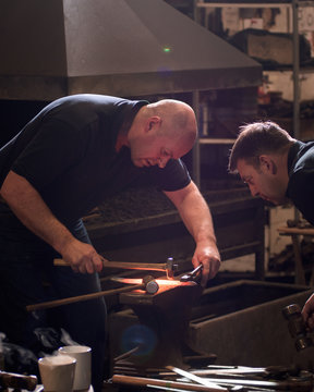 Farriers forging horseshoe on anvil