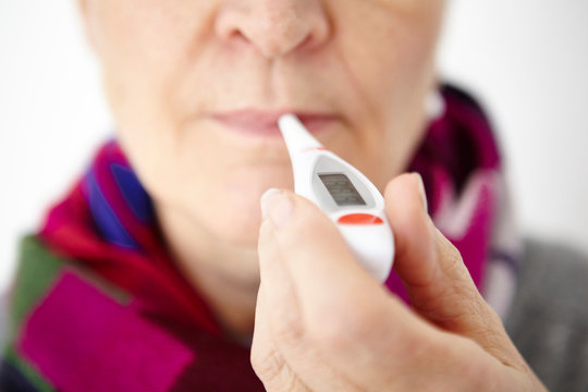 Senior woman holding digital thermometer in mouth, close-up