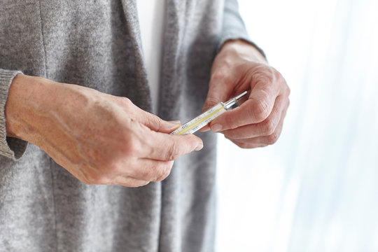 Senior woman holding thermometer, mid section