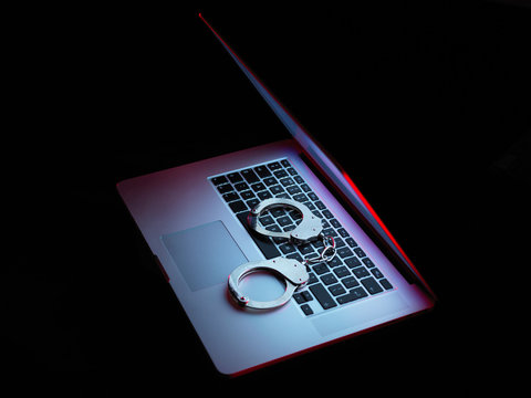 Network security, set of handcuffs sitting on laptop computer