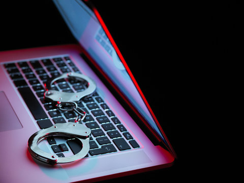 Network security, set of handcuffs sitting on laptop computer