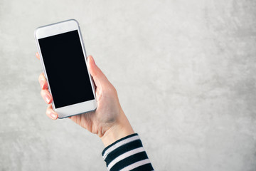 Female hand holding mobile phone with blank mock up screen
