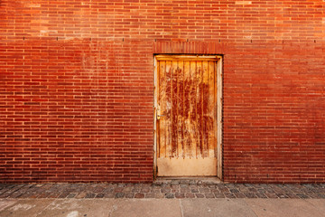 Backdoor, old weathered door and brick wall