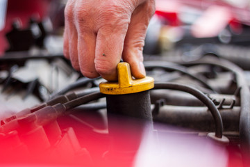 Mechanic checks the oil level in the engine, before pouring in the engine