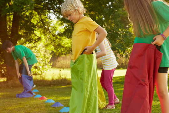 Girls and boys preparing for sack race on start line in park - Powered by Adobe