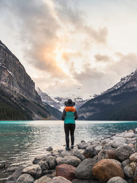 Woman standing at edge of lake, looking at view, rear view, Lake Louise, Alberta, Canada