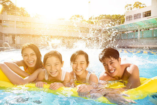 Happy Family Playing In Swimming Pool.