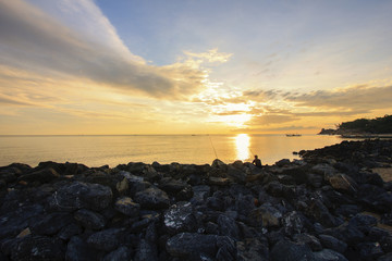 Landscape of sky, sea and breakwater which has one man was fishing at dawn ; Songkhla province, Thailand