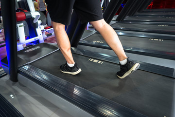 Gym treadmill closeup with man legs running. Concept for exercising, fitness and healthy lifestyle