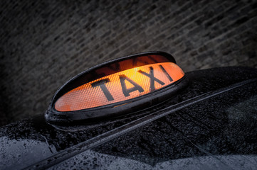 London taxi light in wet backstreet