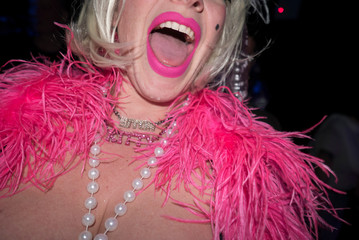 Mid adult woman in party clothes, with pink feather boa and pink lipstick, mid section