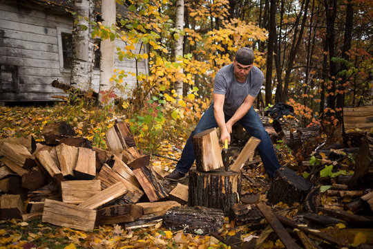 Mid adult man splitting logs in autumn forest, Upstate New York, USA