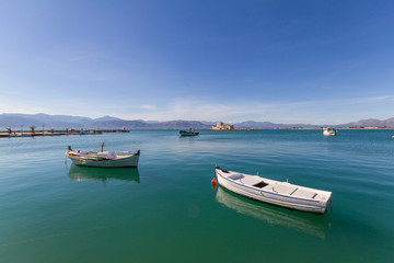 Fototapeta na wymiar Fishing Boats, Lightouse and Bourtzi Fortress in Nafplion, Greece- wide-angle photo