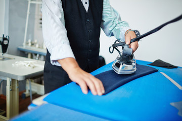 Dress-maker with iron ironing part of unfinished jacket