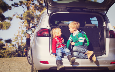little boy and girl travel by car on road in nature