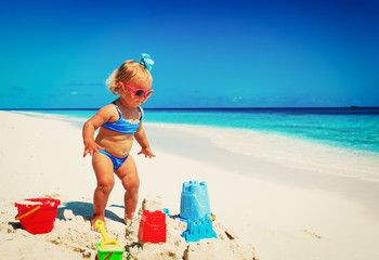 cute little girl play with sand on beach