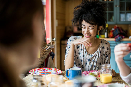 Three friends sitting around table, eating breakfast