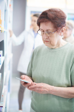Mature woman using smartphone in drug store