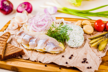 Appetizer. Herring, boiled potato, toasted bread, pickles, onion on wooden board