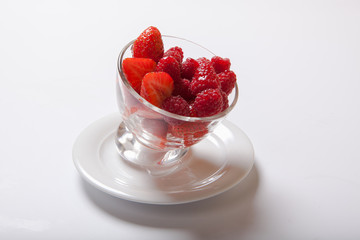 Ripe sweet raspberries in bowl on white table. Fresh raspberry in a transparent glass plate.