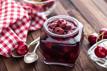 Berries cherry with syrup in a glass jar. Canned fruit