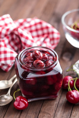 Berries cherry with syrup in a glass jar. Canned fruit
