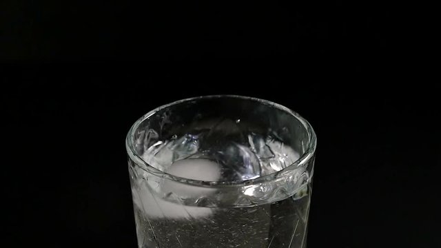 ice cube falling into a glass of water